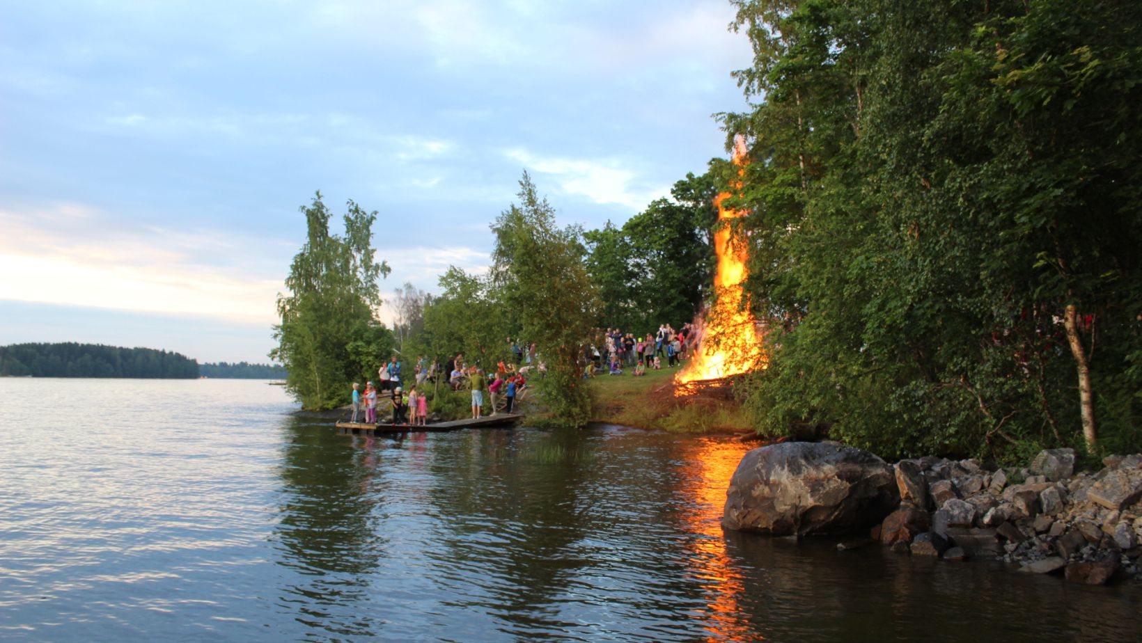 Juhannuskokko ja ihmisjoukko Pappilassa järven rannalla.