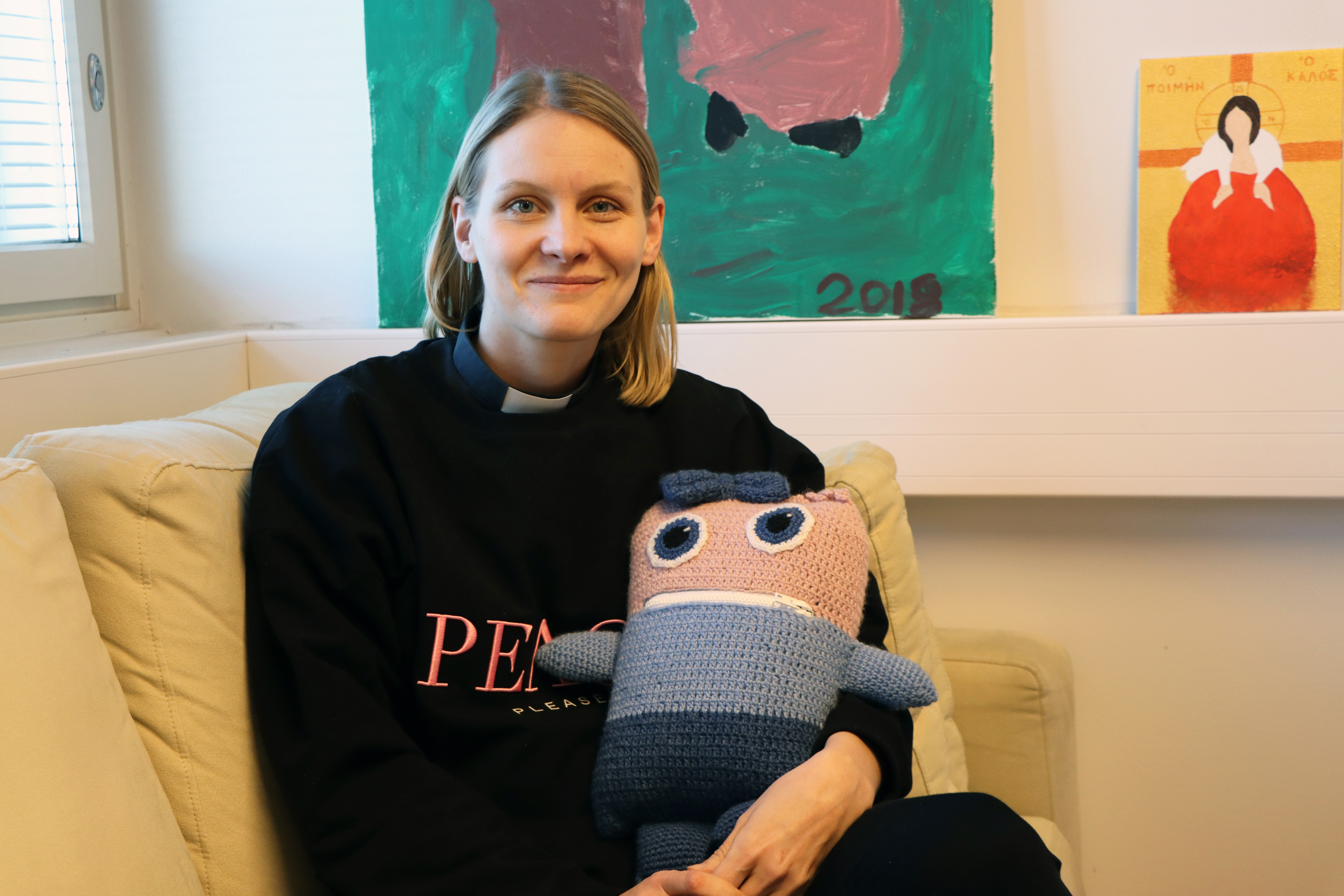 Pappi Reetta Mörttinen istumassa sohvalla.