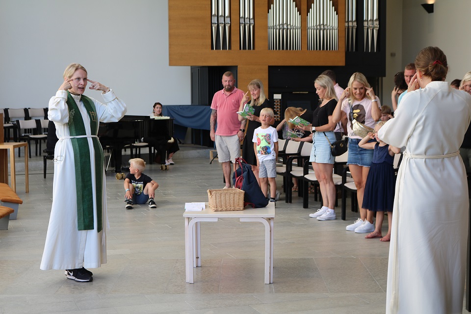 Kouluikäistyön seurakuntapastori Reetta Mörttinen leikittää tulevia koululaisia kirkkohetkessä.