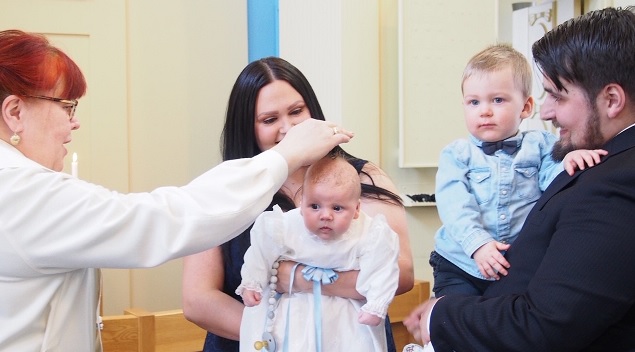 Pappi Denise Gauffin-Kostilainen kastaa Voitto Henrikssonin.