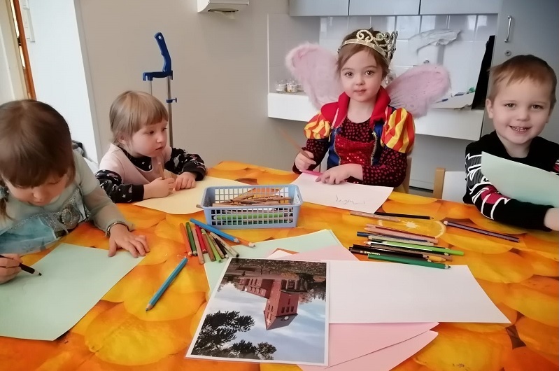 Kirkon päiväkerholaisia pöydän ääressä piirtämässä.
